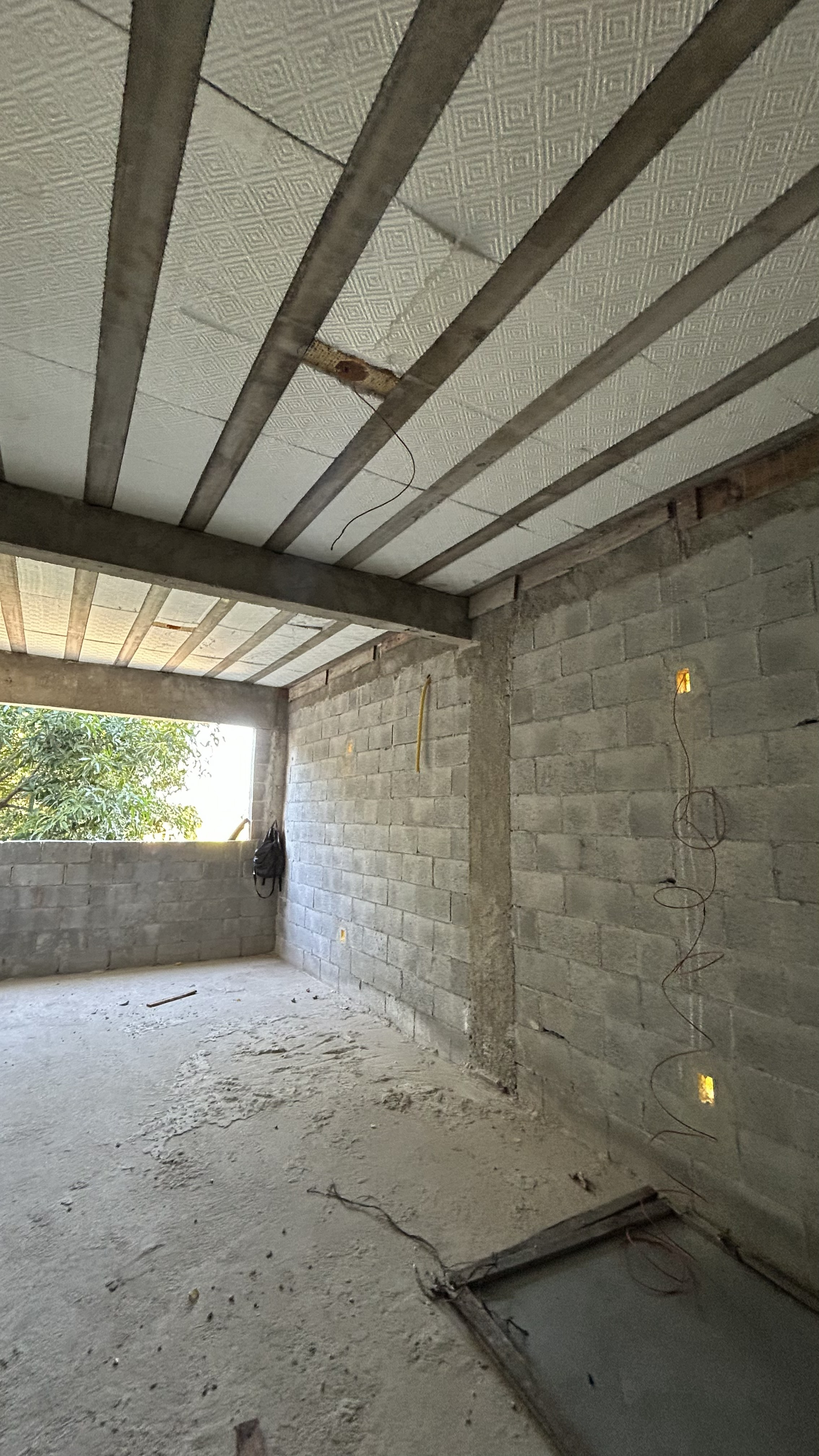 Ambiente em reforma estrutural com vigas de concreto e preparação para rede elétrica