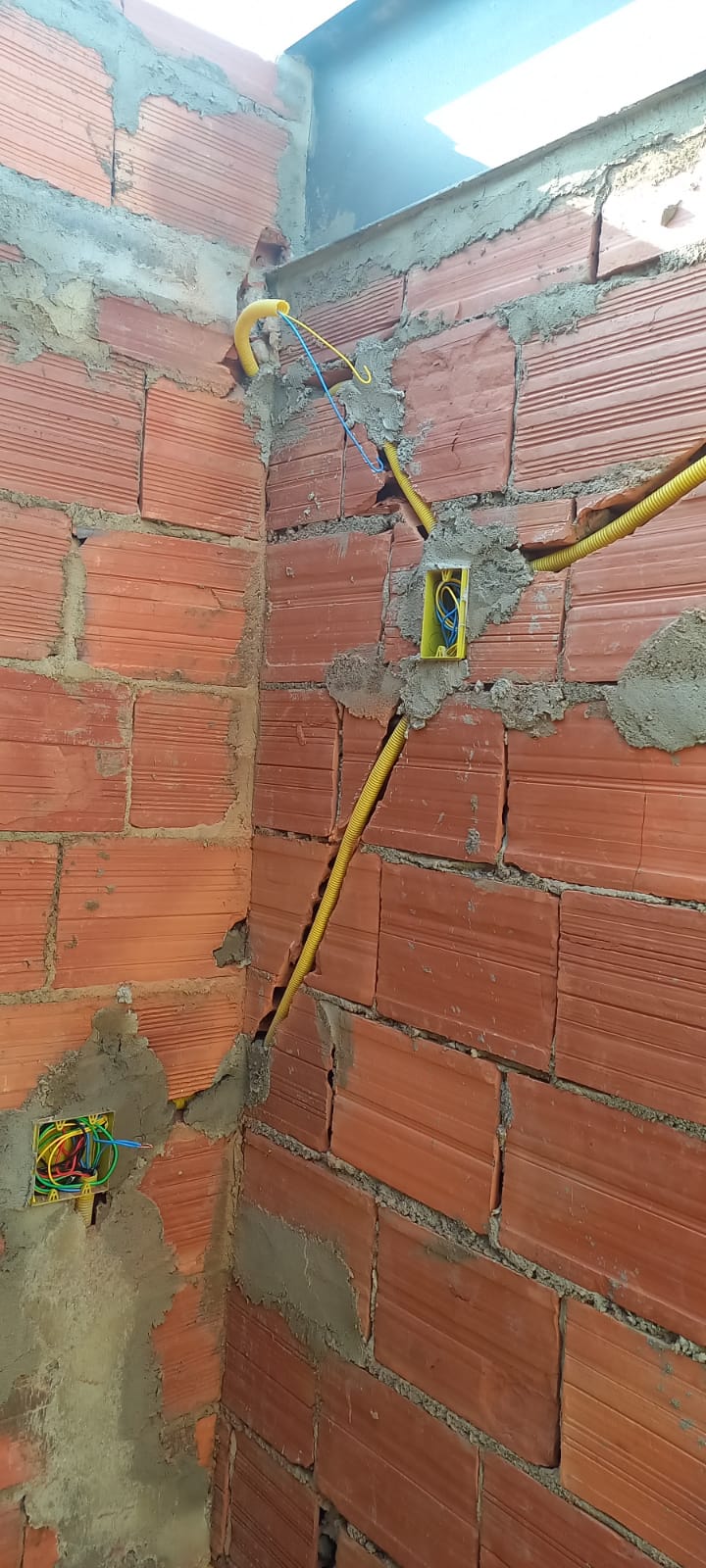 Distribuição de conduítes amarelos e caixas 4x2 chumbadas em alvenaria de tijolos