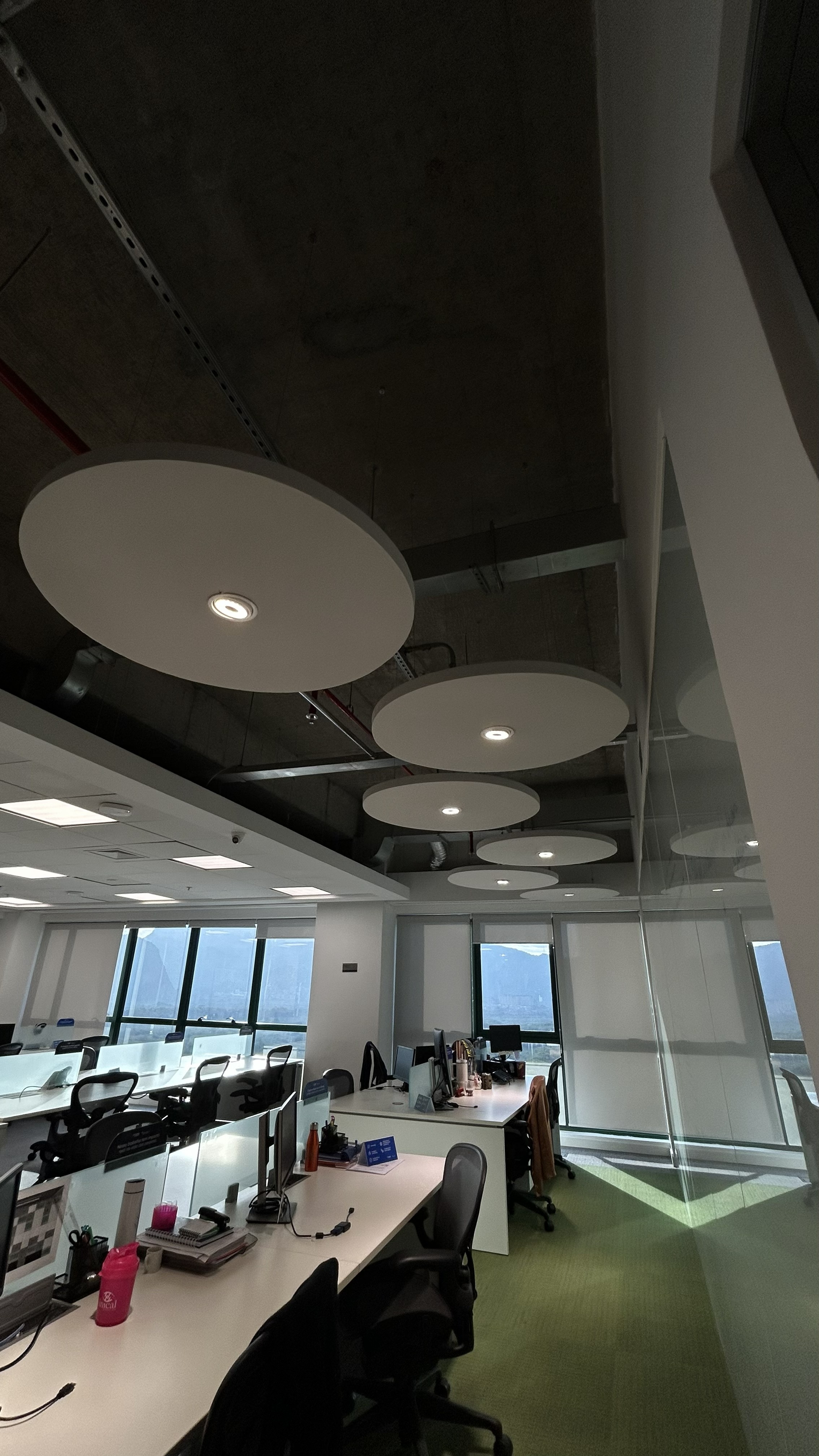 Luminárias circulares pendentes instaladas em escritório corporativo com teto aparente