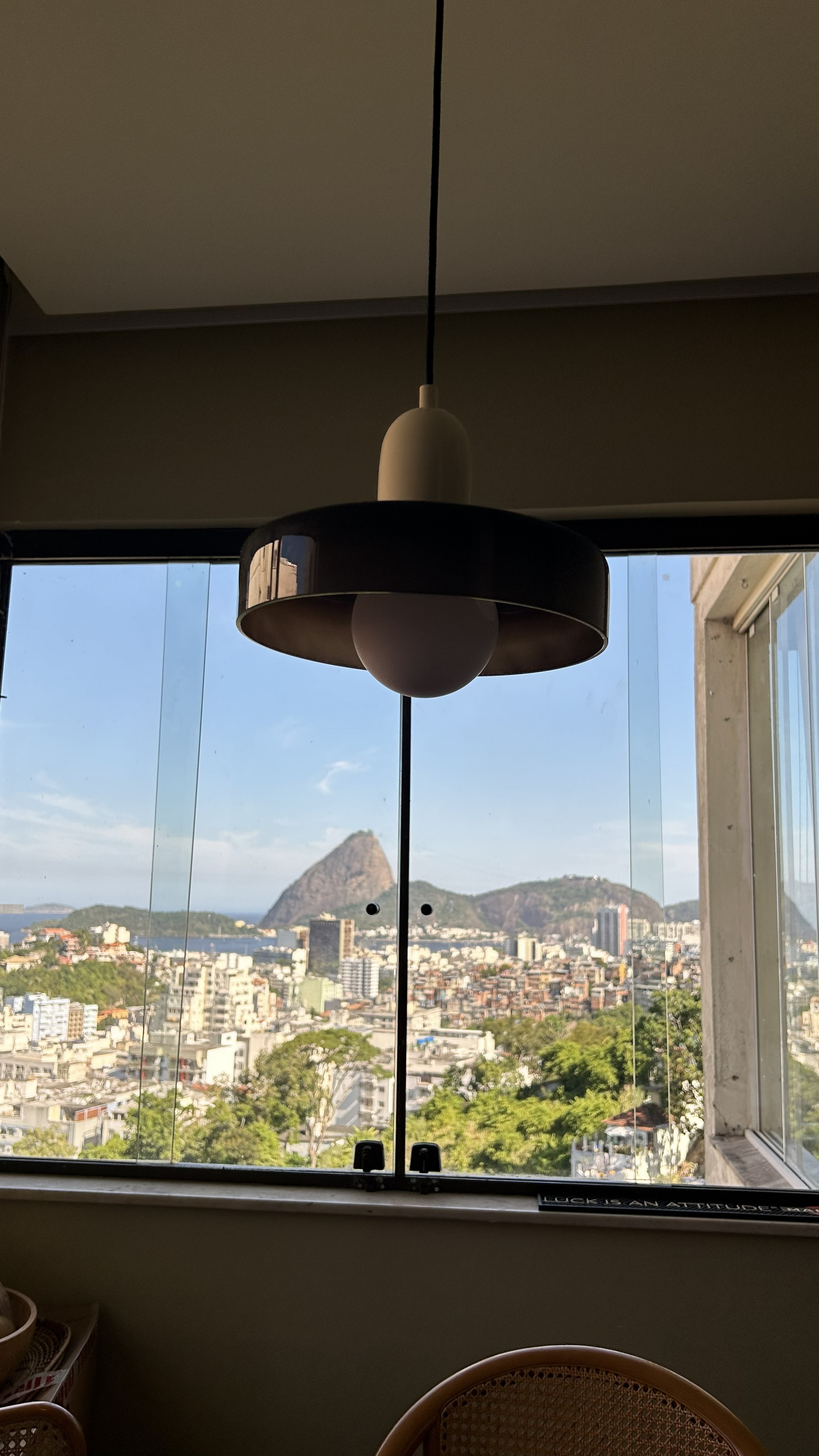 Luminária pendente moderna instalada junto à janela em sala de estar